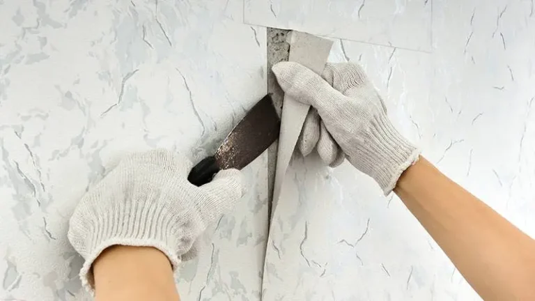 a person using a knife to remove a wallpaper